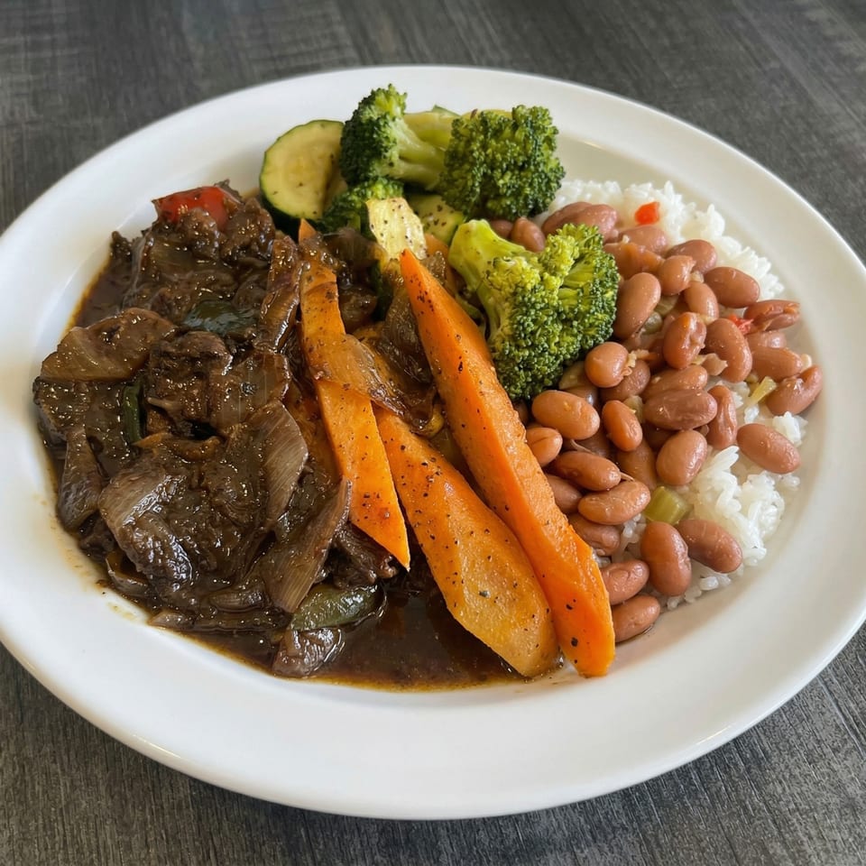 A white plate with beef stew, carrots, broccoli, zucchini, rice, and kidney beans.